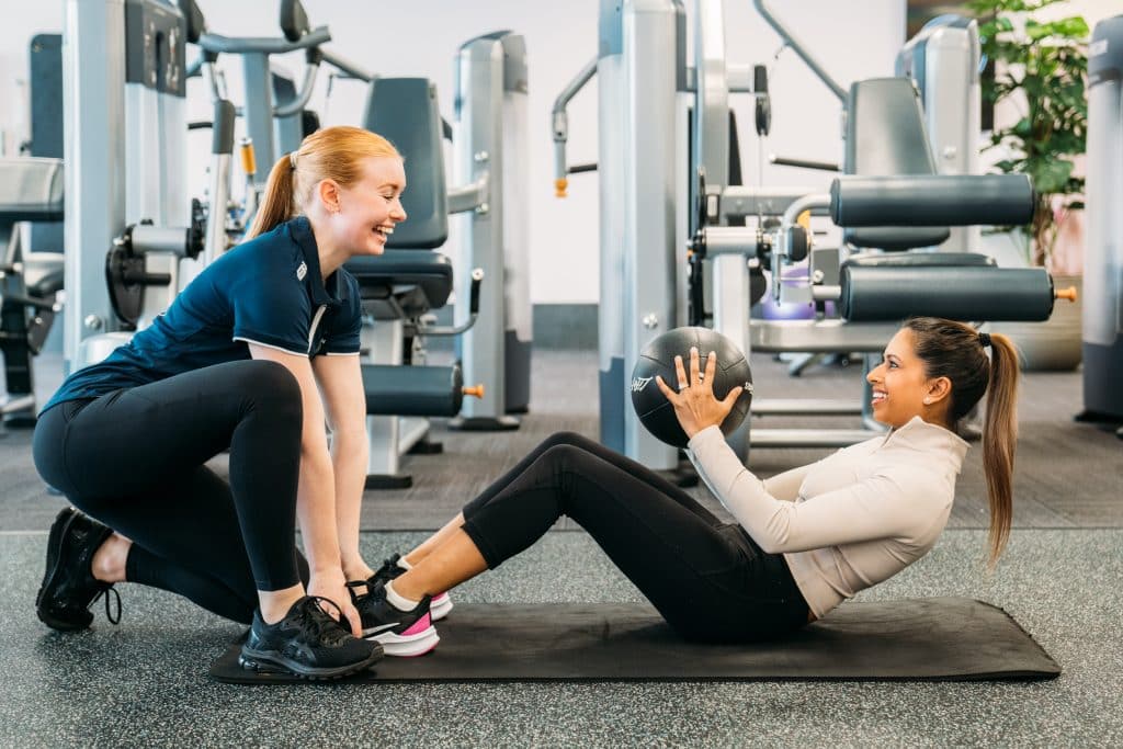 Female personal trainer helping woman do sit ups