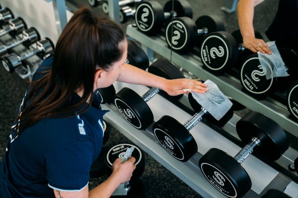 Sista Fitness staff member cleaning the dumbbells