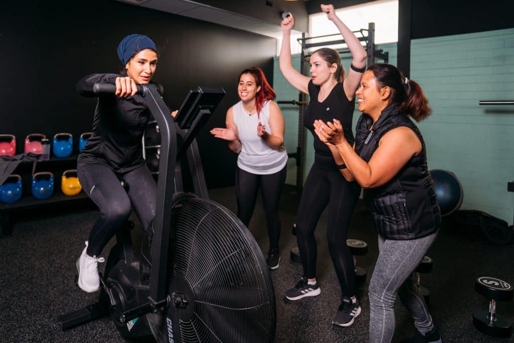 Women cheering on female cyclist at the gym