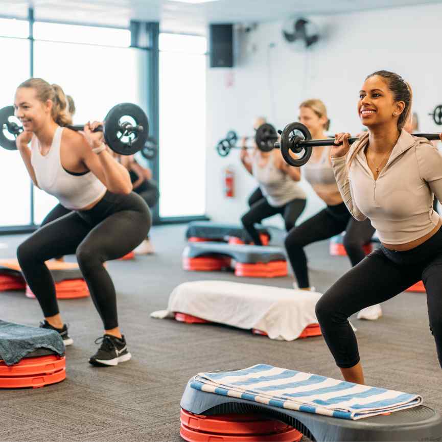 women using barbell during gym class