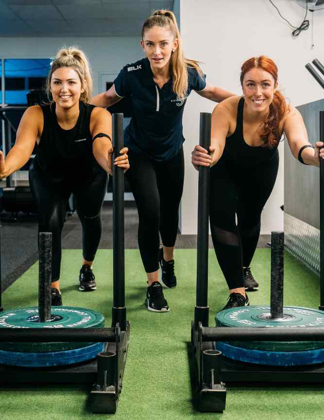 Two female Sista Fitness members pushing weighted sled