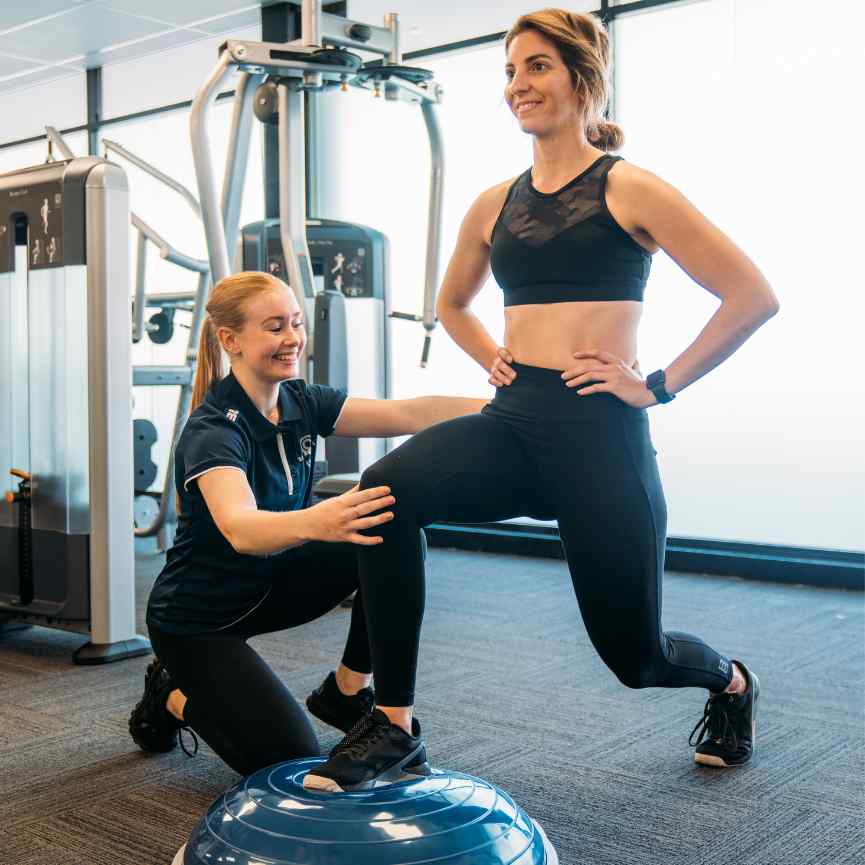 Female personal trainer, helping woman exercise
